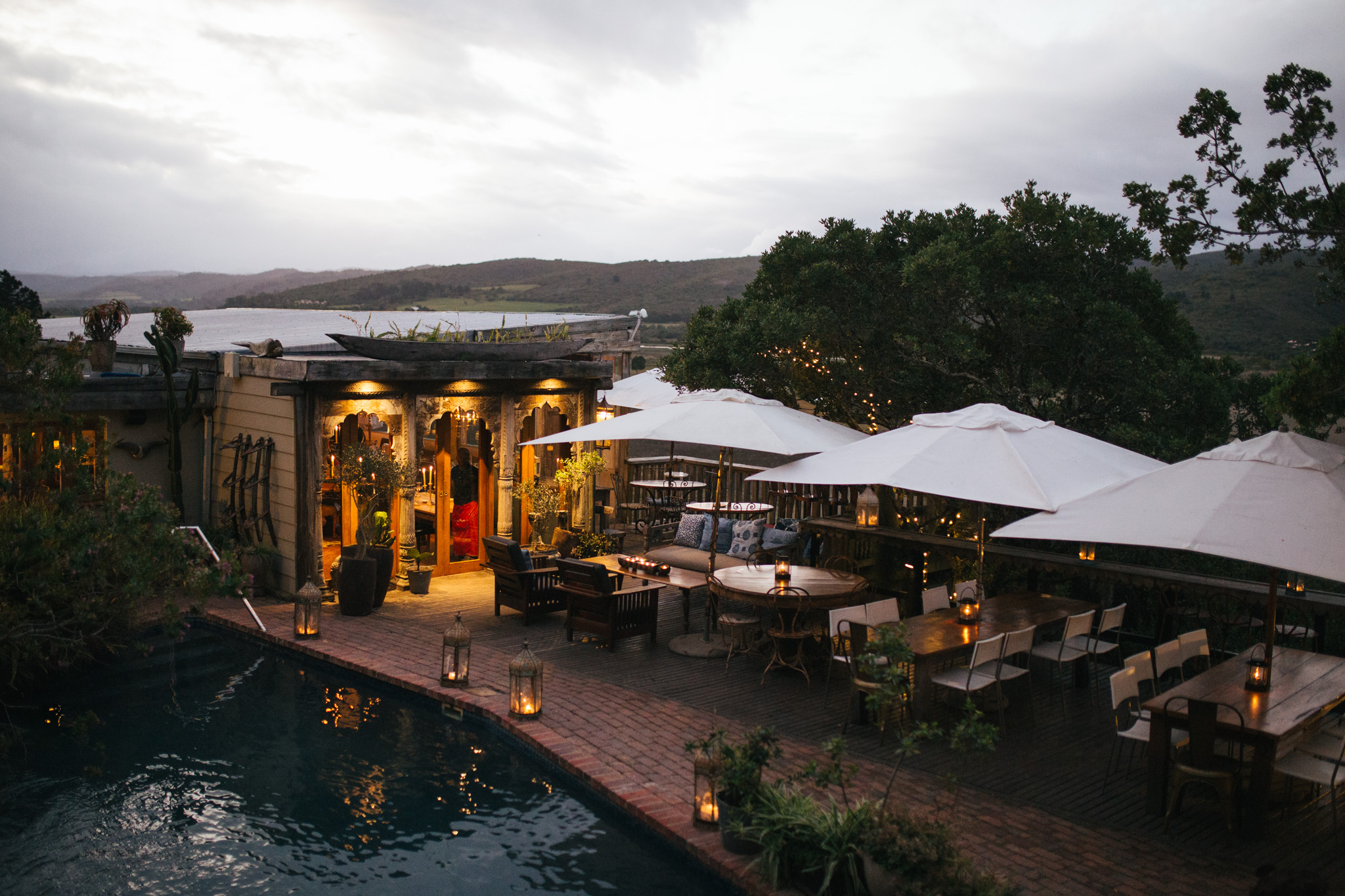 Pierced metal lanterns and hanging plants glowing under a timber roof at a Garden Route lodge