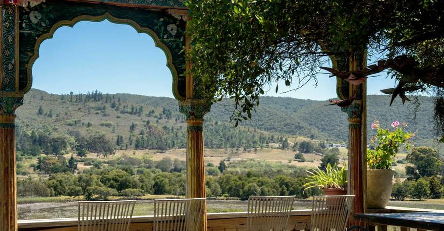 A carved archway on a lodge deck framing the valley and hills beyond